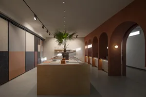 A modern interior design showroom featuring a long display table showcasing various tiles.