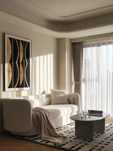 A modern living room featuring a textured fabric sofa, marble coffee table, and sheer curtains allowing soft light to filter 