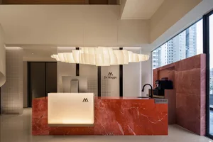 Modern reception desk with red marble countertop and hanging light fixture.
