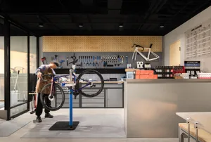 A man repairing a bicycle in an industrial-style bicycle repair shop.