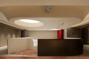 A modern industrial office space featuring sleek concrete walls and a large circular window.