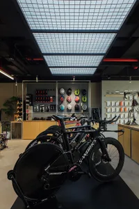 A contemporary bike shop with sleek, black bicycles displayed in a well-lit space with a grid-patterned ceiling panel.