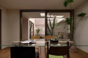 Modern dining room featuring glass furniture and a glass table with plants and drinks.