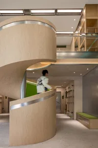 A modern interior design featuring a wooden staircase with a green accent wall.
