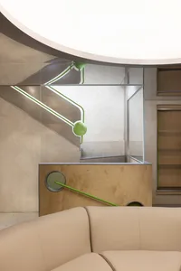 Modern interior space featuring modern concrete staircase with green accents and glass walls.