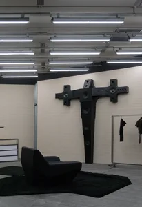 現代客廳內擺放黑色幾何扶手椅，搭配混凝土地板與金屬家具。