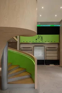 A modern retail shop interior with a green and wooden staircase and a black and green signage area.