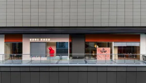 A modern retail storefront with a glass facade and a large red sculpture inside.