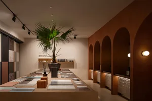 A modern retail storefront showcasing tile displays with a palm plant and warm lighting.