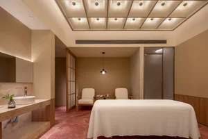 極簡水療室擁有白色大理石牆面、木質家具，以及一張豪華按摩床。