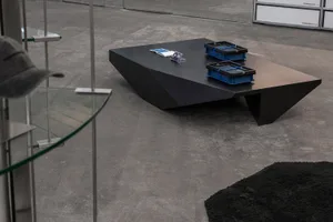 Black metal and concrete coffee table with blue containers and papers on it.
