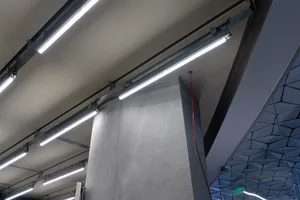 A modern office with concrete ceiling lights and beams, featuring a sleek design.