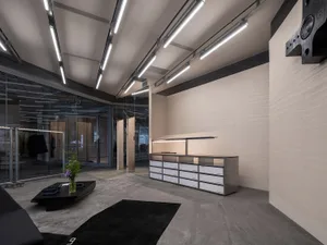 A minimalist office space featuring concrete floors, glass walls, and metal elements.