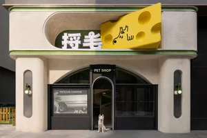 現代寵物店門面，混凝土外牆、大型玻璃窗，以及造型起司塊招牌。