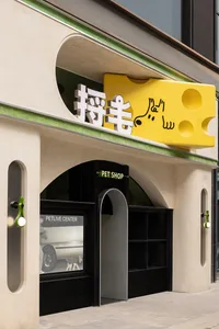 混凝土店面搭配黃色招牌，招牌上以阿拉伯文和英文顯示寵物相關店名。