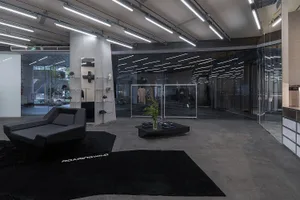 Interior of a modern retail clothing store with industrial design elements, including concrete walls, glass display cases, an