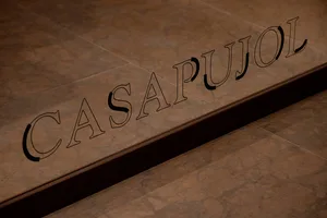 A close-up of a floor sign engraved on textured brown tiles, displaying the word 'CASAPUJOL'.