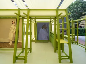 An industrial installation featuring a green wooden structure with a video screen and seating area.