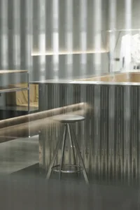A metal bar counter with a stool in an industrial-style setting.