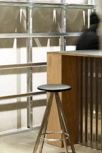 A modern bar stool with a wooden seat and metallic frame.