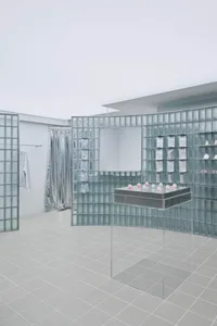 A modern bathroom featuring glass block walls and a clear acrylic pedestal with spherical objects.