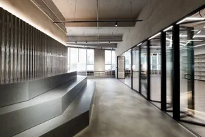 A modern office space featuring concrete and glass materials with an industrial design aesthetic