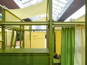 A modern pop-up shop with green and yellow fabric walls and carpeted flooring.