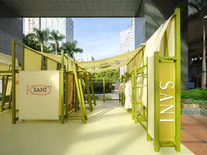 戶外快閃店以綠色框架搭配黃色布料展示商品。