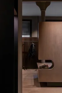 Modern entrance area featuring wooden walls and a coat rack with a black jacket hanging.