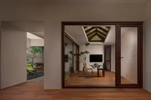 A modern residential interior with wooden flooring, glass windows, and a skylight.