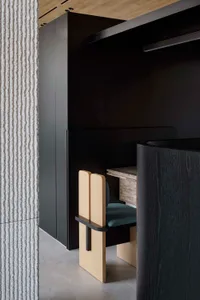 A minimalist workspace with a wooden desk and marble top, featuring dark walls and a textured accent wall.