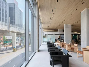 Modern office cafe with concrete walls, glass dividers, and black tables