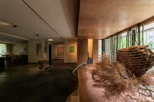 A modern residential interior with concrete floors, bamboo structures, and mixed-media art installations.