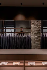 Modern retail store interior featuring dark wooden shelves, brick walls, and glass display cases.
