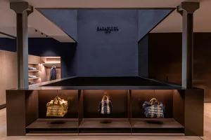 Modern retail store display featuring metallic shelves and bags with branding text.