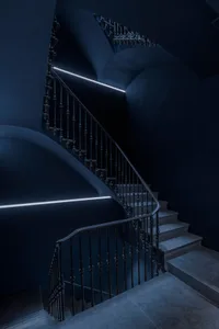 Modern staircase with concrete treads and metal railings against dark walls.