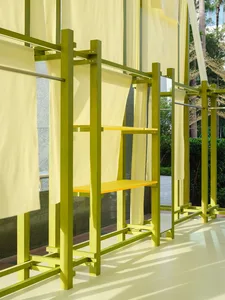 A minimalist fashion runway set featuring yellow curtains and wooden structures with integrated seating and mirrors.