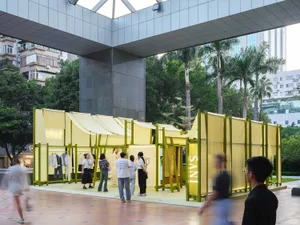 Pop-up store with yellow fabric walls and metal frames in an urban setting.