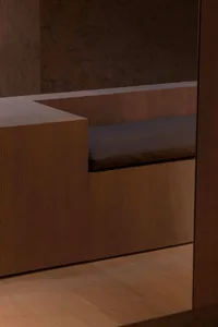 Modern interior design featuring a wooden bench with brown leather cushions and marble walls.