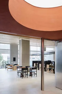 A modern office space featuring concrete, glass, and metal materials in an office lounge area.