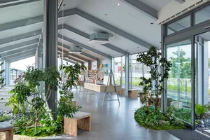 Retail storefront with concrete walls, glass windows, and lush green plants