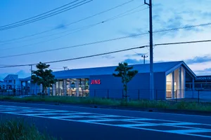 Modern storefront with blue metal cladding, featuring large glass windows and a prominent signage.