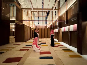 A modern hallway with colorful carpet tiles and a high ceiling with exposed beams.