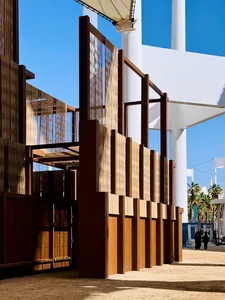 A modern metallic architectural exterior with vertical panels and a clear blue sky in the background.