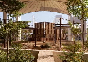 Trees surround a modern pavilion made of wood, concrete, and steel.