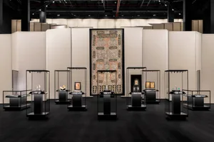 博物館展覽中，各式文物陳列於玻璃展示櫃內，背景為白色牆面。