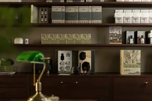 A well-lit bookstore display featuring neatly arranged books on wooden shelves and a green desk lamp.