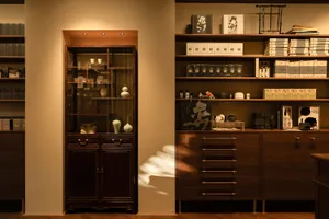 A minimalist retail space featuring wooden furniture, glass cabinets, and a warm, inviting lighting design.