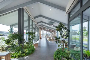 Modern interior of a coffee shop featuring concrete flooring and green plants.