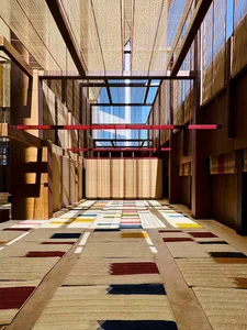 A modern corridor with colorful floor tiles, wooden walls, and concrete flooring under a skylight with natural light streamin